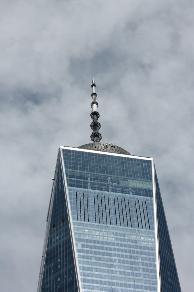 Close-up view of One World Trade Center's spire on a cloudy day in New York City.